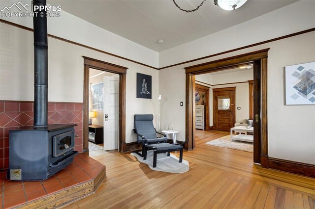 sitting room with light wood finished floors, a wood stove, and baseboards