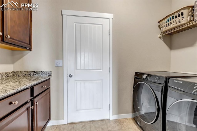 laundry room with light tile patterned flooring, washer and clothes dryer, cabinet space, and baseboards