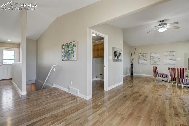 unfurnished living room with light wood finished floors, vaulted ceiling, visible vents, and ceiling fan