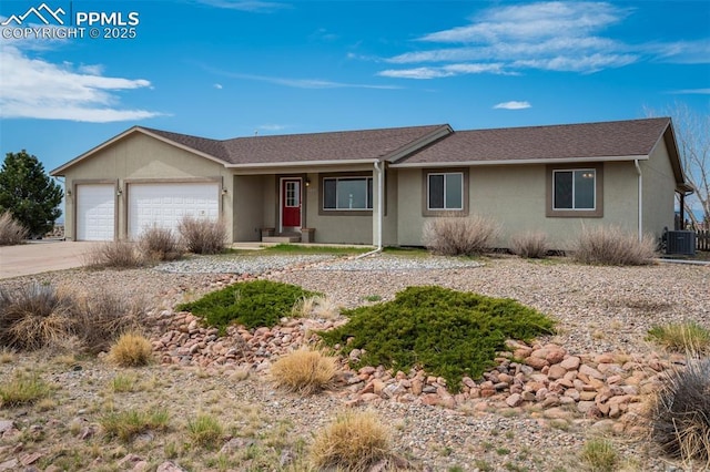 single story home with stucco siding, an attached garage, concrete driveway, and central AC unit