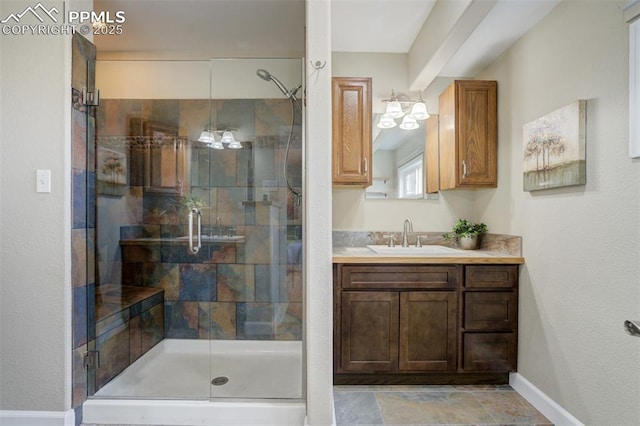 bathroom with baseboards, stone finish floor, vanity, and a stall shower