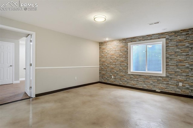 spare room with baseboards, visible vents, and finished concrete flooring