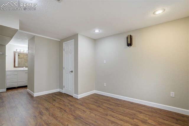 basement featuring recessed lighting, wood finished floors, baseboards, and a sink