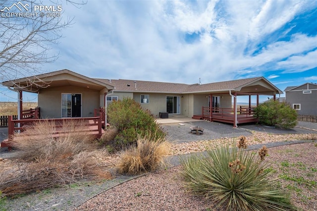 back of house featuring stucco siding, a wooden deck, and a patio