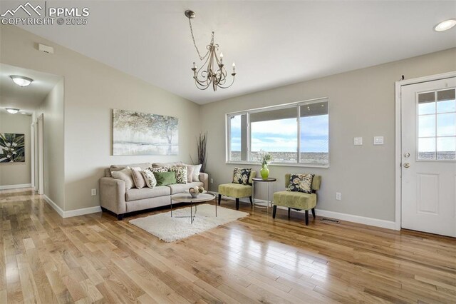 living area featuring a chandelier, light wood-style flooring, a healthy amount of sunlight, and visible vents