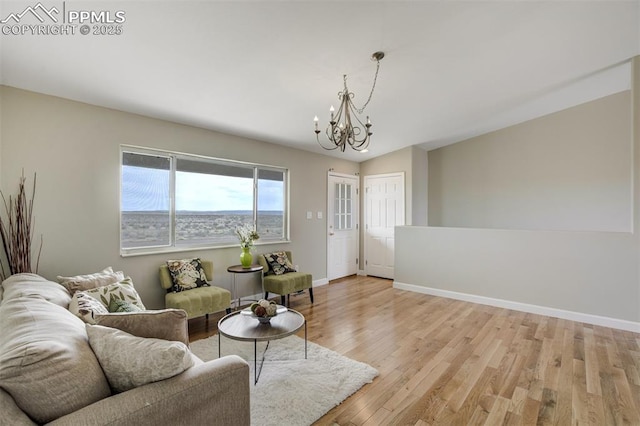 living area featuring baseboards, an inviting chandelier, and light wood-style floors