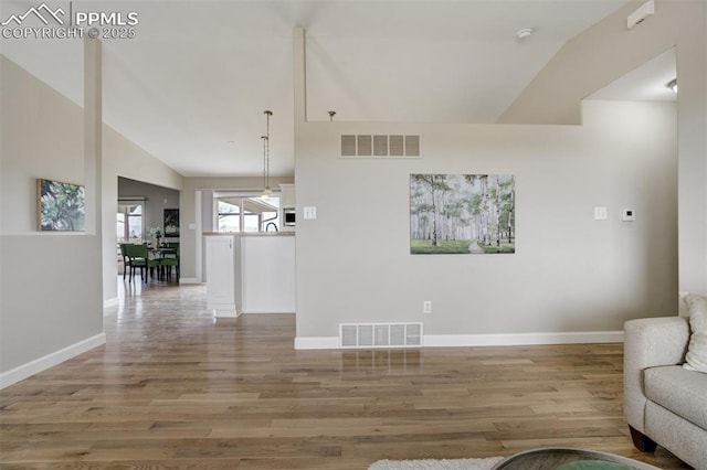 living room featuring lofted ceiling, light wood-style floors, visible vents, and baseboards