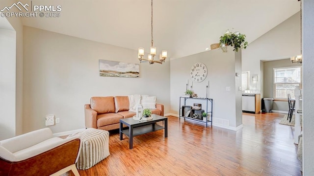 living room with a chandelier, light wood-type flooring, and baseboards