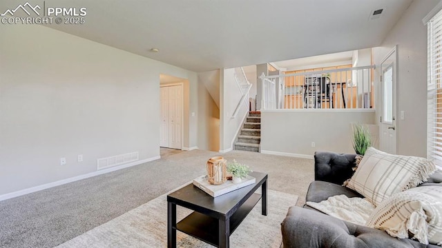 living area with baseboards, visible vents, carpet flooring, and stairs