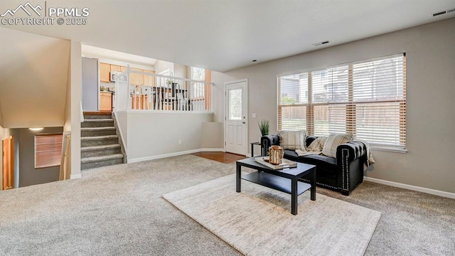 living room featuring baseboards, visible vents, carpet flooring, and stairs