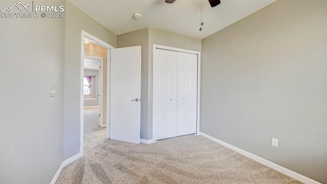 unfurnished bedroom with carpet floors, a closet, baseboards, and ceiling fan