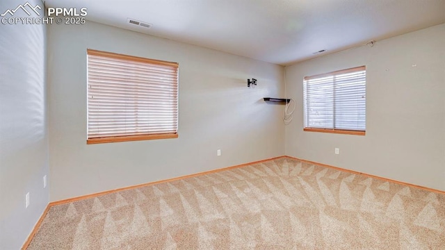 carpeted spare room featuring visible vents and baseboards