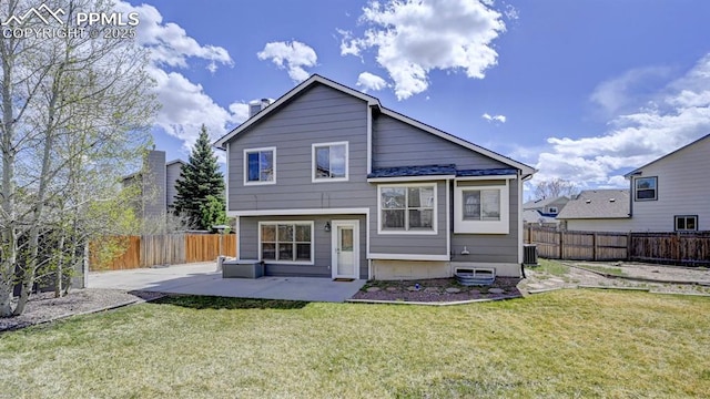 back of house featuring a patio area, a lawn, a chimney, and a fenced backyard