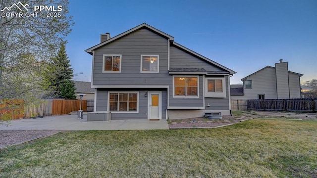 back of house featuring a yard, a patio area, a fenced backyard, and a chimney