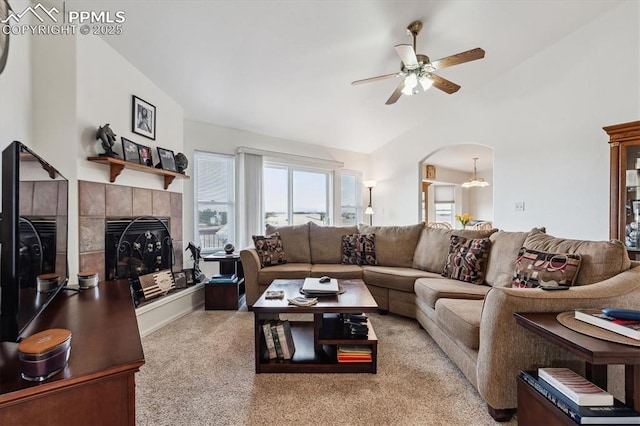 13255 Woodlake Rd, Elbert, CO 80106 - carpeted living area featuring ceiling fan, lofted ceiling, arched walkways, and a tiled fireplace
