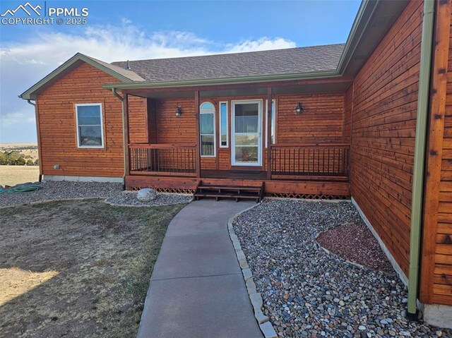 13255 Woodlake Rd, Elbert, CO 80106 - doorway to property with a porch and roof with shingles