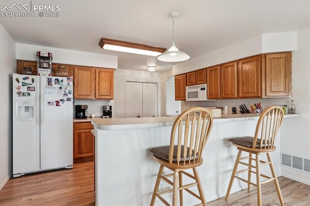 13255 Woodlake Rd, Elbert, CO 80106 - kitchen featuring a kitchen breakfast bar, white appliances, light wood-style flooring, and brown cabinets