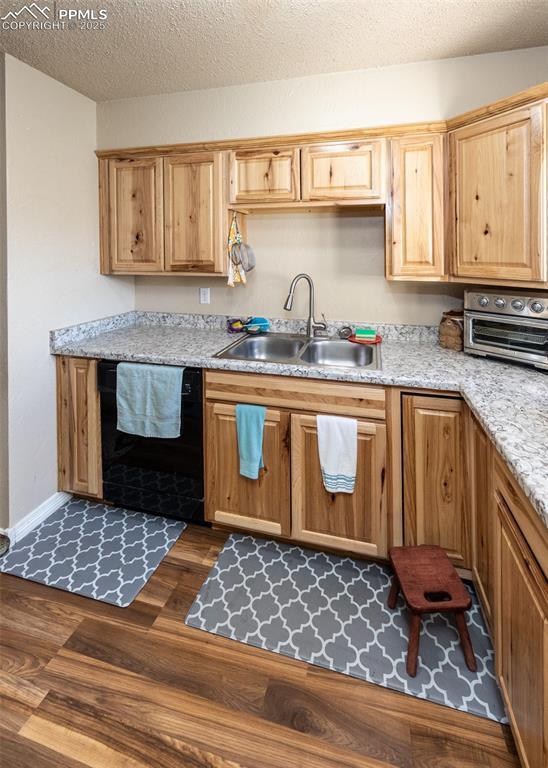 2914 Del Mar Cir, Colorado Springs, CO 80910 - kitchen featuring black dishwasher, a sink, dark wood-type flooring, light countertops, and a textured ceiling