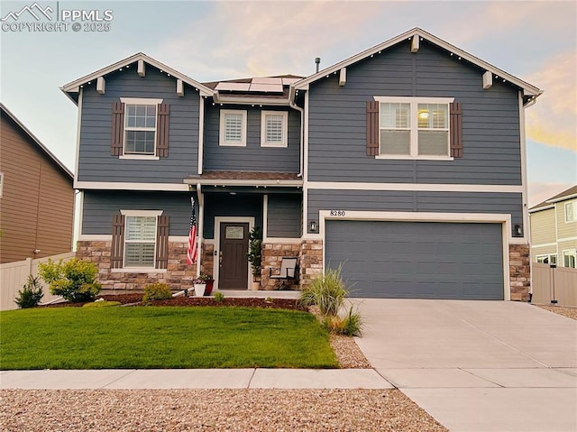 craftsman-style home with a garage, a front lawn, roof mounted solar panels, and stone siding