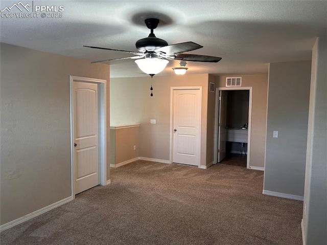 empty room with a ceiling fan, visible vents, carpet floors, and baseboards