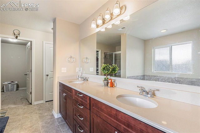 bathroom featuring a stall shower, double vanity, a sink, and visible vents