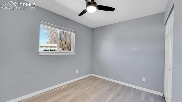 spare room with baseboards, visible vents, wood finished floors, and ceiling fan