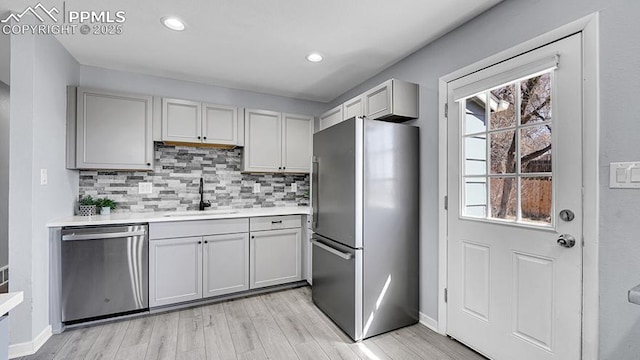kitchen featuring light countertops, decorative backsplash, a sink, and stainless steel appliances