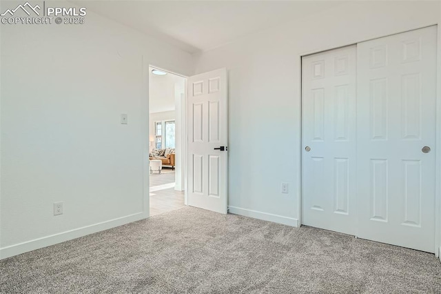 unfurnished bedroom with baseboards, a closet, and carpet flooring