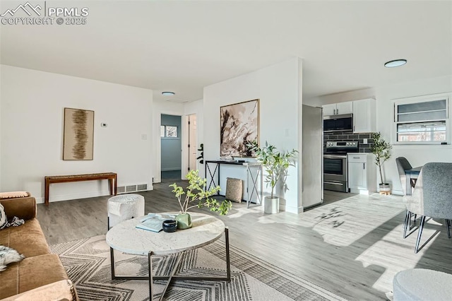 living room featuring baseboards, visible vents, and wood finished floors
