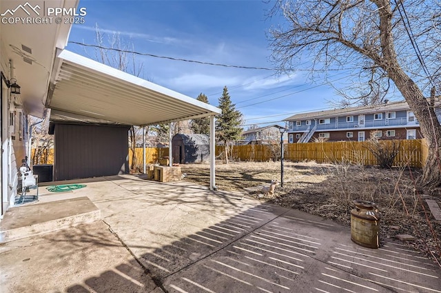 view of patio featuring a shed, cooling unit, an outbuilding, and fence