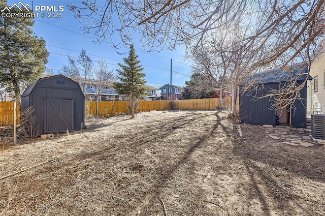 view of yard with cooling unit, a fenced backyard, an outbuilding, and a storage shed