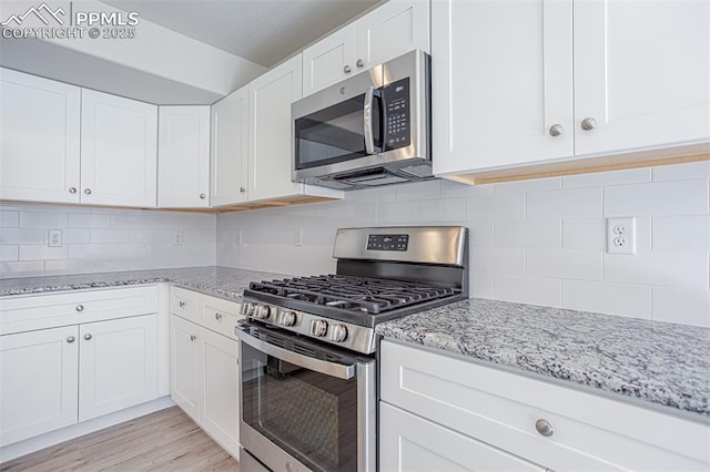 7372 Cornice Pt, Colorado Springs, CO 80923 - kitchen with tasteful backsplash, light wood-type flooring, white cabinets, light stone countertops, and appliances with stainless steel finishes