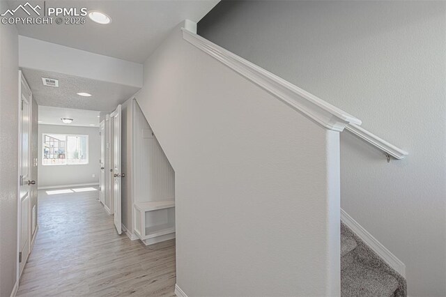 7372 Cornice Pt, Colorado Springs, CO 80923 - hallway with baseboards, light wood-style flooring, visible vents, and stairway