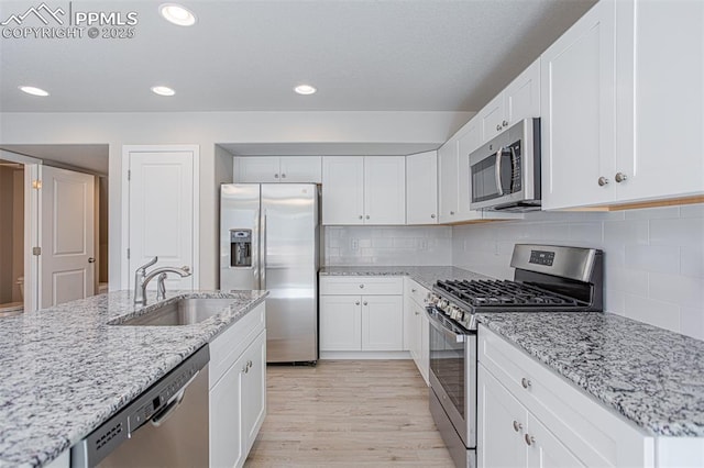 7372 Cornice Pt, Colorado Springs, CO 80923 - kitchen featuring recessed lighting, stainless steel appliances, a sink, light wood-style floors, and white cabinets