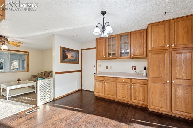 6745 Fielding Cir, Colorado Springs, CO 80911 - kitchen with light countertops, dark wood-type flooring, visible vents, glass insert cabinets, and brown cabinets