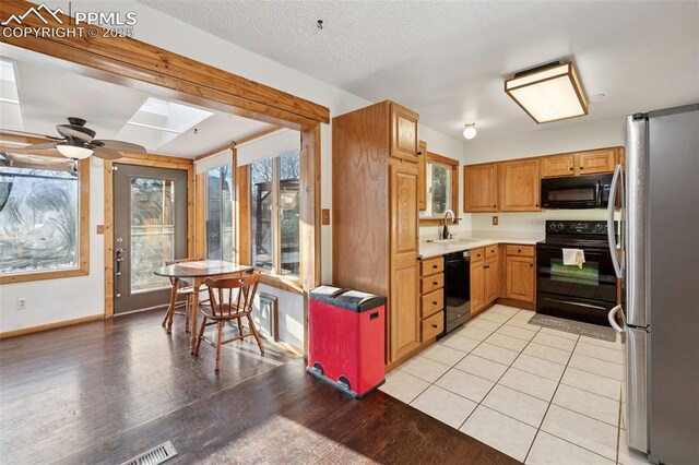 6745 Fielding Cir, Colorado Springs, CO 80911 - kitchen with light countertops, a sink, a skylight, black appliances, and ceiling fan