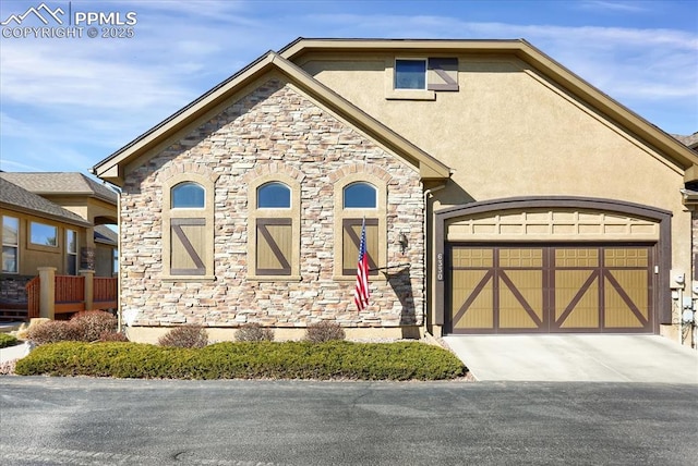 view of front of house featuring driveway, stucco siding, and stone siding