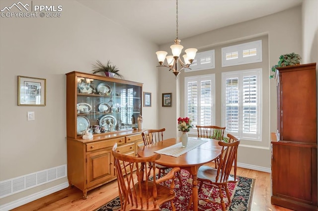 dining area with baseboards, light wood-type flooring, visible vents, and a chandelier