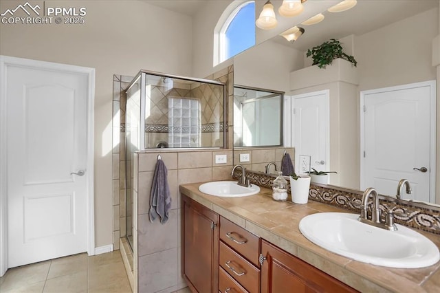 full bathroom with a shower stall, tile patterned floors, double vanity, and a sink