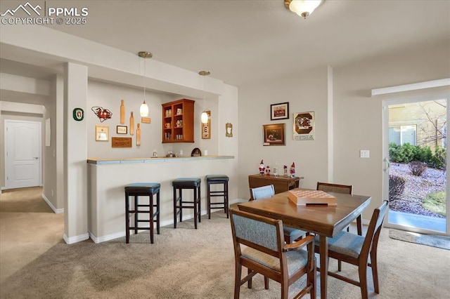 carpeted dining room with wet bar and baseboards