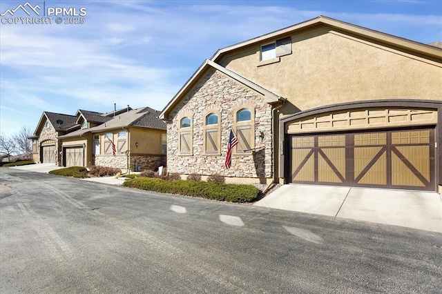 view of front facade with stone siding, a garage, and stucco siding