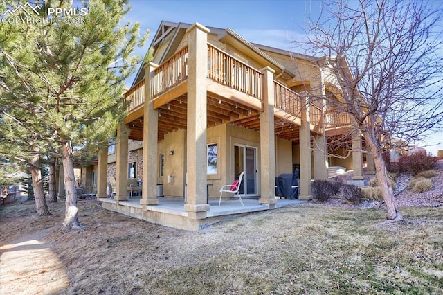 rear view of house with stucco siding, a patio, and a deck