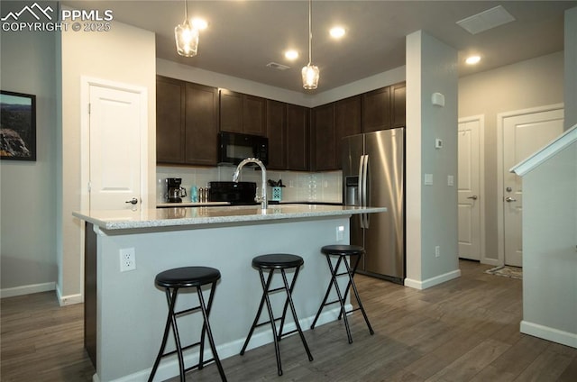 kitchen featuring backsplash, black microwave, stainless steel fridge with ice dispenser, dark wood-type flooring, and dark brown cabinets