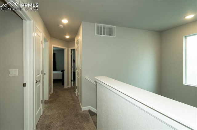 hall featuring recessed lighting, baseboards, dark carpet, and visible vents