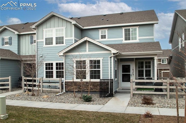 view of front of home featuring stone siding, a shingled roof, and board and batten siding