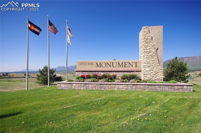 community / neighborhood sign with a mountain view and a yard