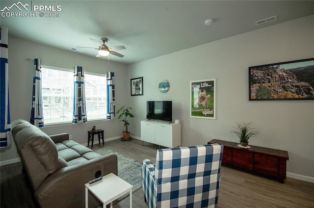 living room with baseboards, visible vents, a ceiling fan, and wood finished floors