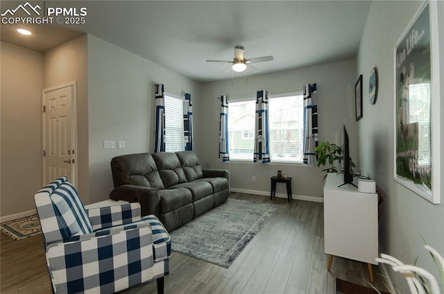 living area featuring baseboards, wood finished floors, and ceiling fan