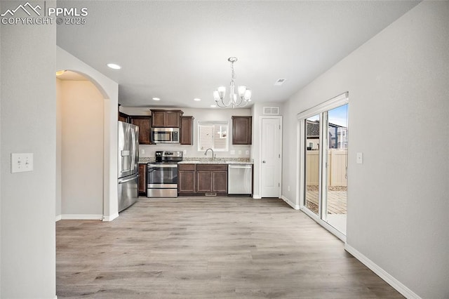 7718 Benecia Dr, Fountain, CO 80817 - kitchen featuring dark brown cabinetry, arched walkways, a chandelier, appliances with stainless steel finishes, and a sink