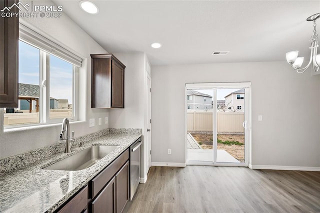 7718 Benecia Dr, Fountain, CO 80817 - kitchen with visible vents, a sink, light wood-type flooring, dark brown cabinetry, and light stone countertops